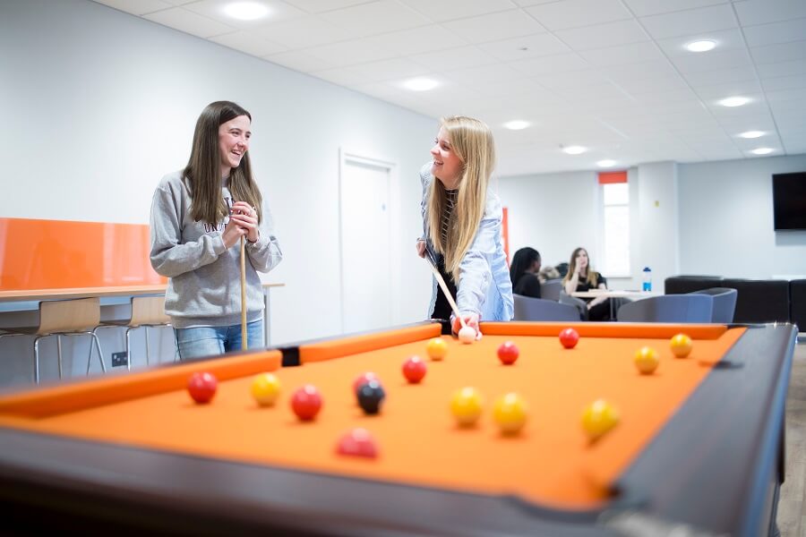 Students playing pool in accommodation common room