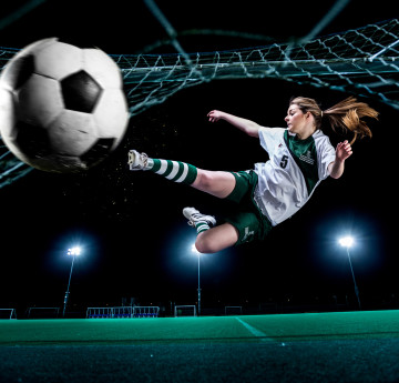Football girl kicking a ball towards the camera