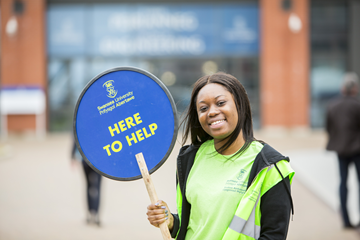 Student ambassador holding a here to help sign
