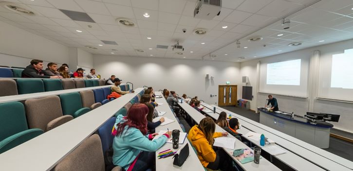 Lecture theatre with tiered seating, students, and large presentation screen
