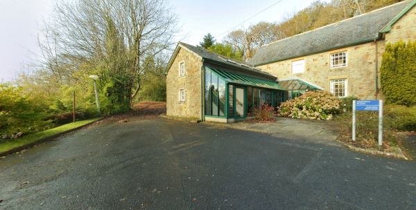 Stone library building with glass entrance set among trees and grounds