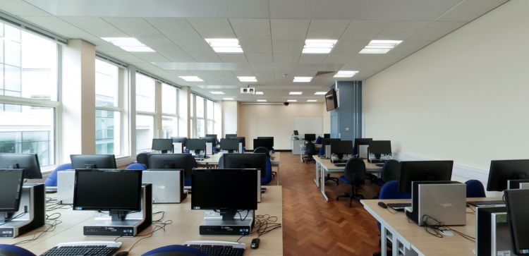 IT computer lab with rows of desks, monitors, and large windows.