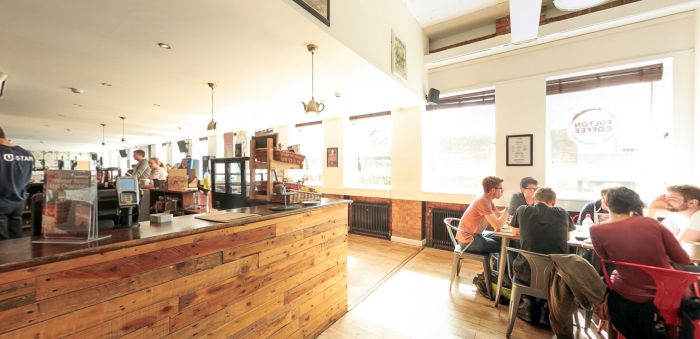 Cafe seating area with wooden counter and students dining by windows