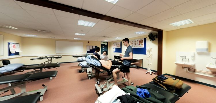 Osteopathic practical suite with treatment tables and clinical training session