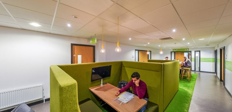 Student using a study booth with desk seating in a communal area