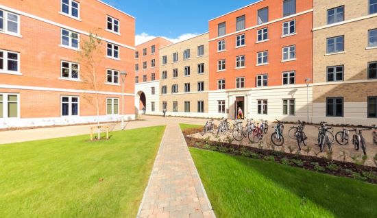 Courtyard with grass and paths surrounded by multi‑storey brick buildings