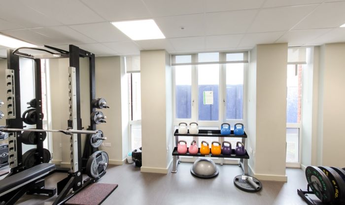 Gym with weights, kettlebells, and two people using strength equipment.